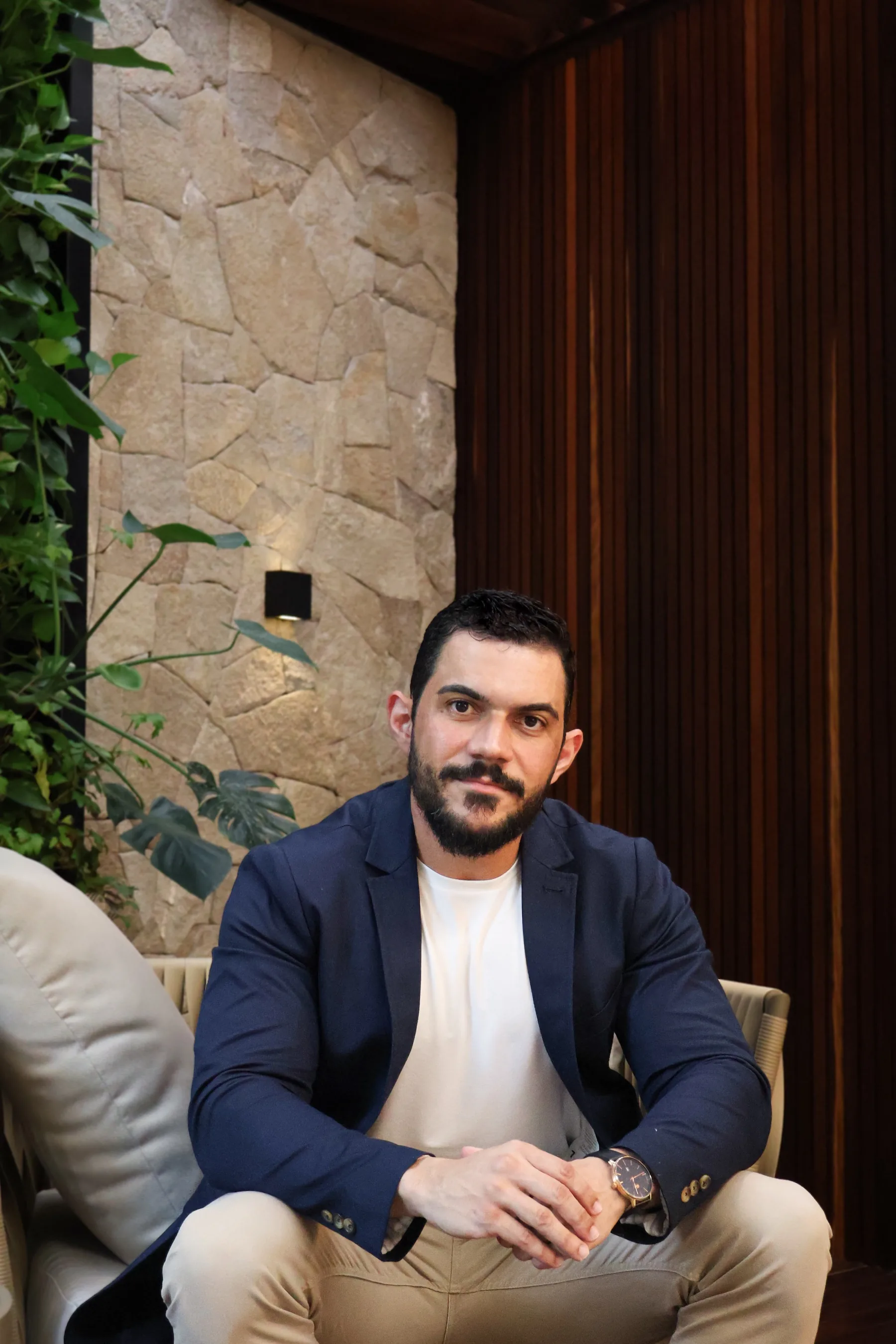 Dr. Caio Sodré sentado em ambiente de madeira e pedra